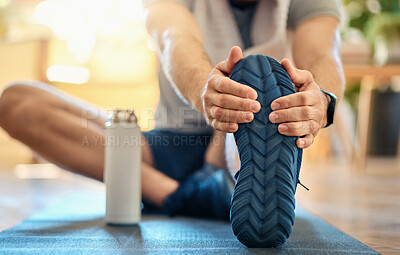 Buy stock photo Closeup of one active caucasian man touching his feet and stretching legs for warmup to prevent injury while exercising at home. Bottom sole of shoes of guy preparing for training workout  on a mat on the floor