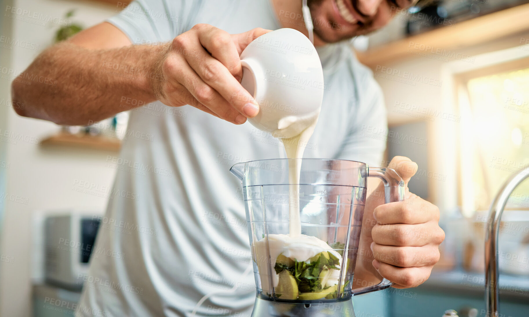 Buy stock photo Closeup of one caucasian man pouring yoghurt into blender for healthy green detox smoothie in kitchen at home. Guy having fresh fruit juice to cleanse and provide energy for training. Wholesome drink with vitamins and nutrients