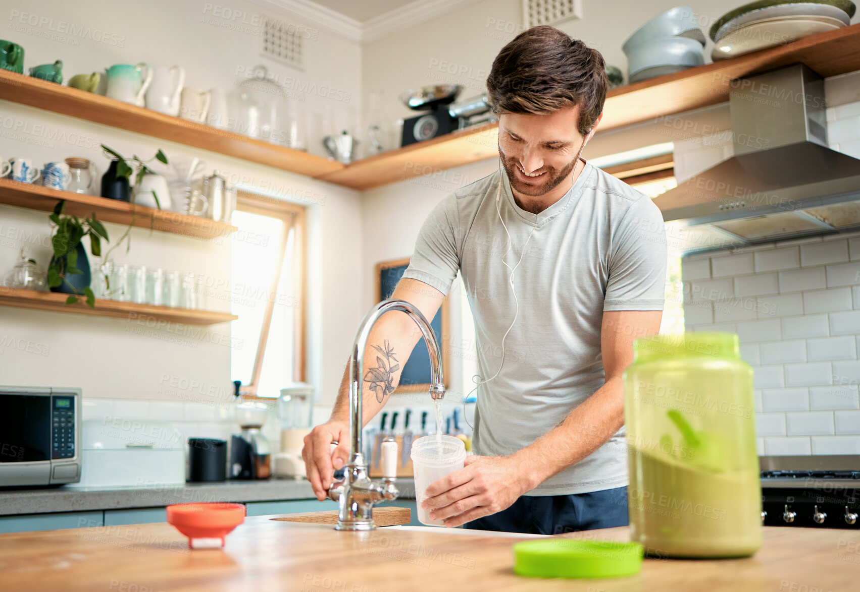 Buy stock photo One fit young caucasian man pouring water into a bottle for chocolate whey protein shake for energy for training workout in a kitchen at home. Guy having nutritional sports supplement for muscle gain and dieting with weightloss meal replacement