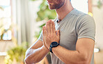 Closeup of one caucasian man meditating in harmony with hands together in namaste gesture while practising yoga at home. Calm, relaxed and focused guy feeling zen while praying quietly for stress relief and peace of mind