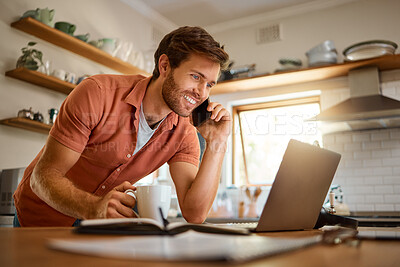 Young caucasian businessman on a call using a cellphone while working on a laptop and drinking coffee at home alone. Happy male businessperson smiling and talking on a cellphone while working in the kitchen at home