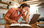 Young amazed caucasian businessman working on a laptop at home alone. One shocked male businessperson looking surprised while working in the kitchen at home