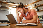 Young tired caucasian businessman working on a laptop from home alone. One stressed businessman looking unhappy while using a laptop. Person looking upset and worried