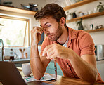 Young caucasian businessman suffering from a headache while working on a laptop from home alone. One stressed man looking unhappy while using a laptop. Person looking upset and worried