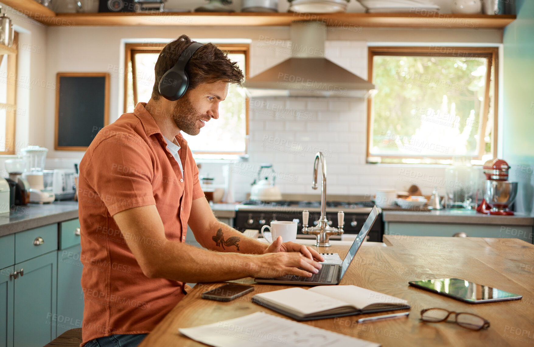 Buy stock photo Headphones, home kitchen and man on laptop streaming music, online social media or reading web info, news or blog. Smile, typing and person listening to audio podcast while working remote on project