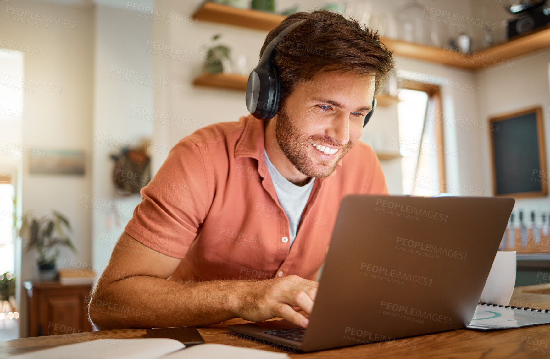 Buy stock photo Headphones, laptop and remote work, happy man in kitchen on video call, social media meme or networking for online job. Technology, smile and freelancer on internet for webinar listening to podcast.