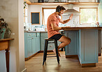 Young cheerful caucasian businessman wearing headphones and waving his hand greeting on a virtual meeting on a laptop at home alone. One joyful male businessperson smiling while working in the kitchen at home