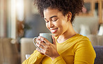 Young happy mixed race woman holding and drinking a cup of coffee at home. One cozy hispanic female smiling and enjoying a cup of tea while relaxing at home