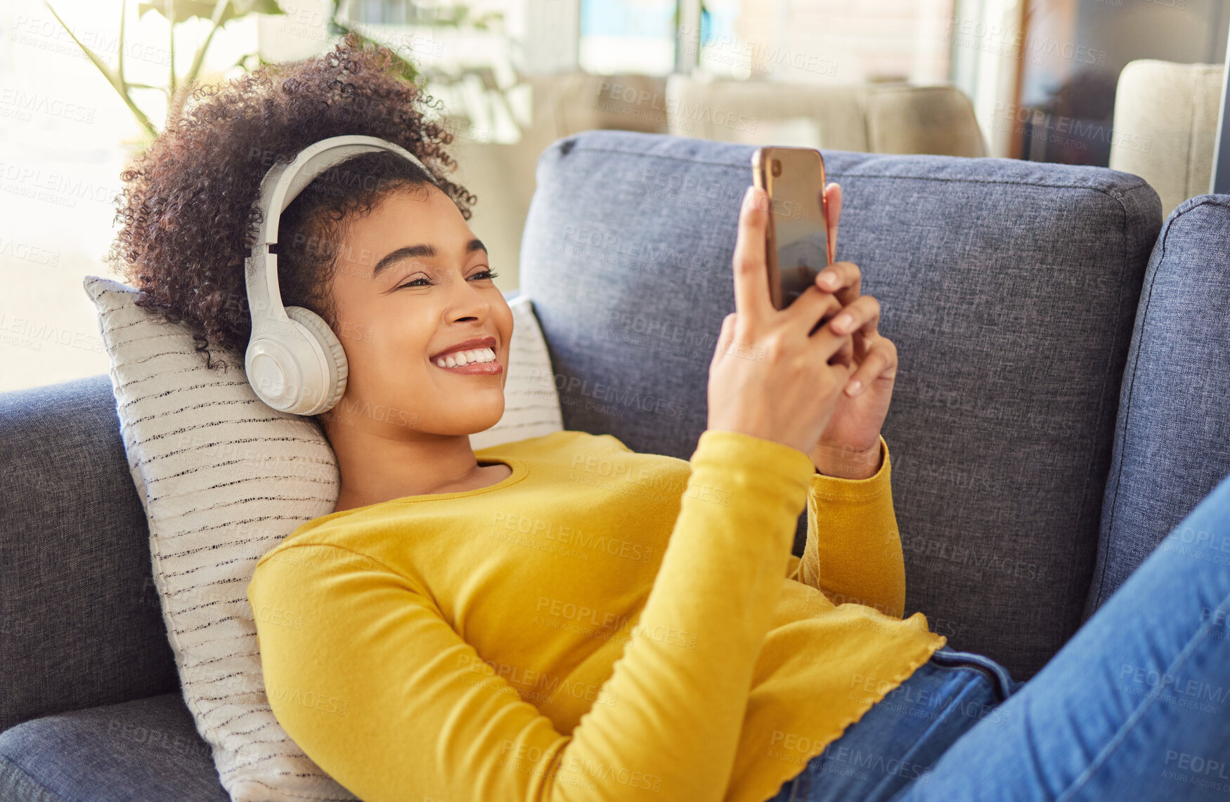 Buy stock photo Headphones, phone and woman relax on sofa with home networking, social media and happy music streaming. Mobile app, audio electronics and young african person on couch, web listening or internet chat