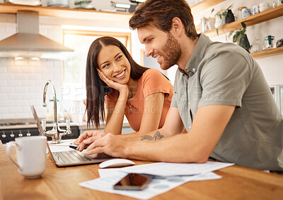 Buy stock photo Young cheerful interracial couple bonding while working on a laptop together at home. Caucasian boyfriend and girlfriend working through their bills and using a laptop. Content wife staring at her husband while typing on a computer