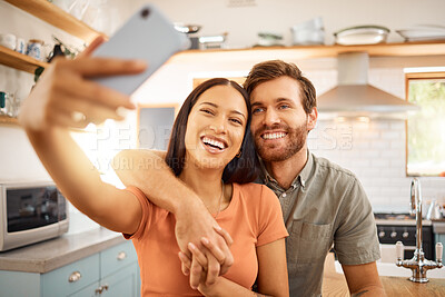 Young content interracial couple taking a selfie with a phone together at home. Joyful mixed race girlfriend taking a photo with her caucasian boyfriend on a cellphone. Happy husband and wife relaxing and spending time together in the morning