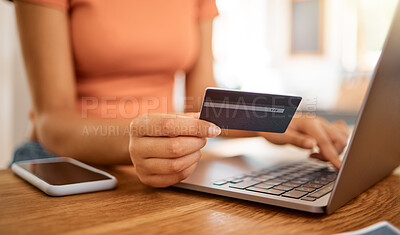 Buy stock photo Businesswoman using a credit card and laptop while working from home. Business professional making an online payment holding a debit card and working on a laptop at home