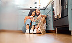 Young happy interracial couple bonding while drinking coffee together at home. Loving caucasian boyfriend and mixed race girlfriend sitting on the kitchen floor. Cheerful husband and wife relaxing and spending time together