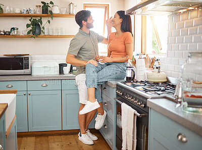 Buy stock photo Young cheerful interracial couple bonding while drinking tea together at home. Loving caucasian boyfriend and mixed race girlfriend standing in the kitchen. Content husband and wife relaxing and spending time together in the morning
