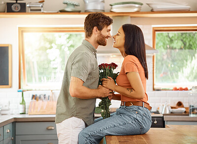 Buy stock photo Young content caucasian boyfriend giving his cheerful mixed race girlfriend a bouquet of flowers at home. Happy hispanic wife receiving roses from her husband. Interracial couple bonding together at home