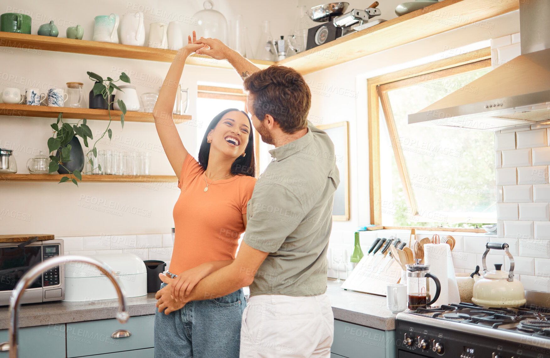 Buy stock photo Young content interracial couple dancing in the kitchen at home. Playful caucasian boyfriend and mixed race girlfriend having fun. Happy husband and wife relaxing and spending time together in the morning