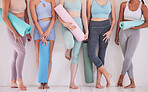Closeup of women ready for yoga class. Feet of group of women standing in yoga studio. Friends being social, talking before yoga class. Women in wellness yoga class with mats