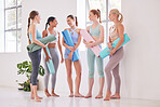 Happy women talking before class. Group of friends bonding in a yoga studio. Happy friends talking holding yoga mats in a class. Fit friends ready for holistic yoga exercise