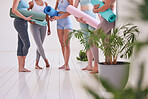 Feet of women standing in a yoga studio cropped. Group of friends ready for yoga practice. Women holding yoga equipment in the studio. Women waiting for pilates practice to begin. wait