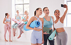 Happy friends taking a selfie before yoga class. Group of women taking a photo on a cellphone before pilates class. Young women bonding before an exercise class. Women using cellphone in yoga class