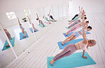 Group of women in side plank in pilates studio. Group of women doing yoga class together. Women balance their body in yoga studio. Group of women exercise in pilates class together