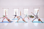 Group of women in downward dog pose. Young women in downward dog with a leg stretched. Dedicated women stretching together in a pilates class. Group of women practice yoga routine together