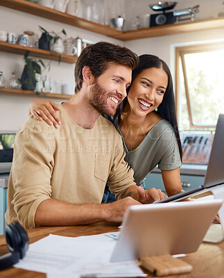 Buy stock photo Beautiful young wife standing behind her husband working on his laptop while they look at the screen together and smile. Happy young interracial couple surfing the internet and enjoying work from home