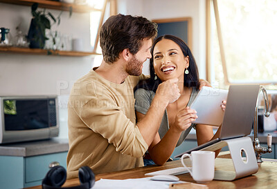 Buy stock photo Happy young interracial couple calculating their budget using wireless devices at home. Smiling young caucasian man working on laptop and lovingly touching his hispanic wifes face while she browses social media on digital tablet