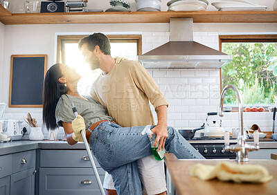 Buy stock photo Cheerful young interracial couple dancing while cleaning their home together. Young caucasian man and hispanic woman having fun while doing chores in the kitchen