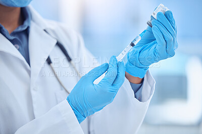 Buy stock photo doctor wearing gloves and preparing a vaccine by removing liquid out of a vial with a syringe while working at a hospital. A doctor removing fluid from a vial with a syringe at a clinic