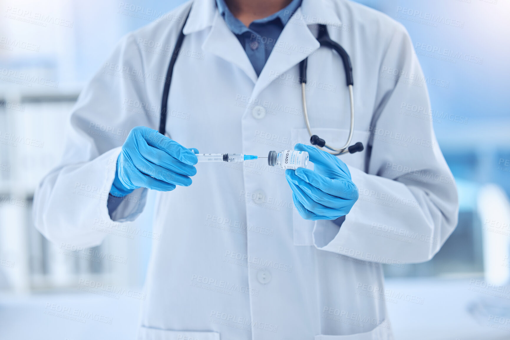 Buy stock photo doctor wearing a labcoat and gloves preparing a covid vaccine while working in a hospital. Unrecognizable scientist removing liquid from a vial using a syringe while working at a lab