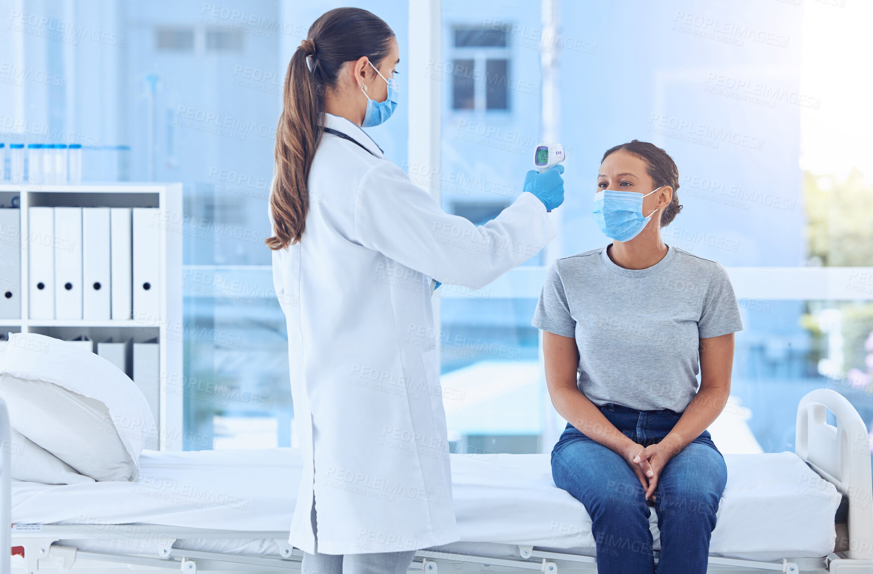 Buy stock photo patient having her temperature checked with a thermometer. Doctor using a thermometer to scan a patients temperature. Patient in consult with doctor for corona virus. Gp in checkup with covid patient