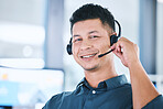 Portrait of one happy hispanic call centre telemarketing agent talking on a headset while working in an office. Confident friendly male consultant operating a helpdesk for customer service and sales support
