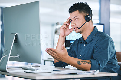 One stressed and confused hispanic call centre agent talking on headset while working on broken computer in an office. Anxious male consultant having problems with slow internet connection failure error while panic with crisis and difficult customers