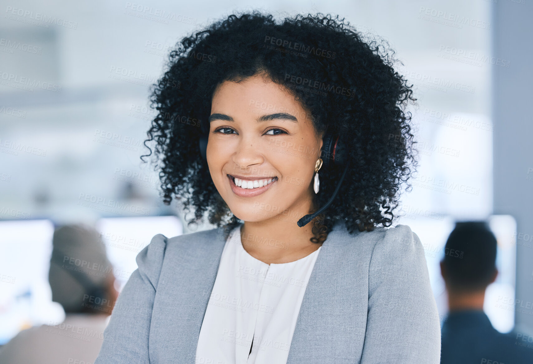 Buy stock photo Portrait of confident young mixed race call centre telemarketing agent talking on headset while working in a call centre with her colleagues in the background. Face of manager and supervisor operating helpdesk for customer service and sales support