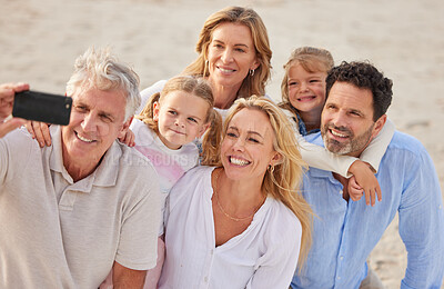 Buy stock photo Closeup of a senior caucasian couple at the beach with their children and grandchildren taking a selfie with a smartphone. Caucasian family relaxing on the beach having fun and bonding