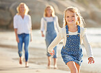 Portrait of an adorable little girl running and smiling on the beach during summer. Cute little girl having fun outdoors with the family