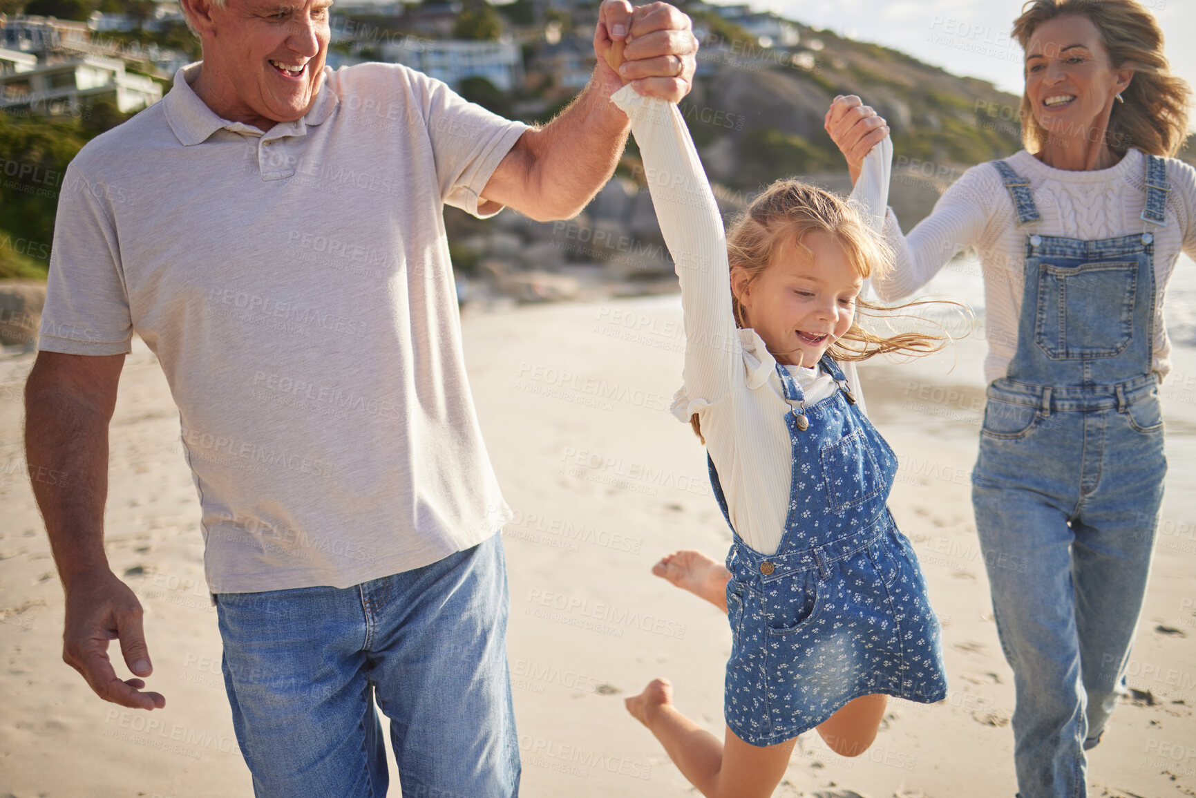 Buy stock photo Adorable little girl smiling while walking and playing  on the beach with his grandparents and holding hands. Cute caucasian girl enjoying family time at the beach