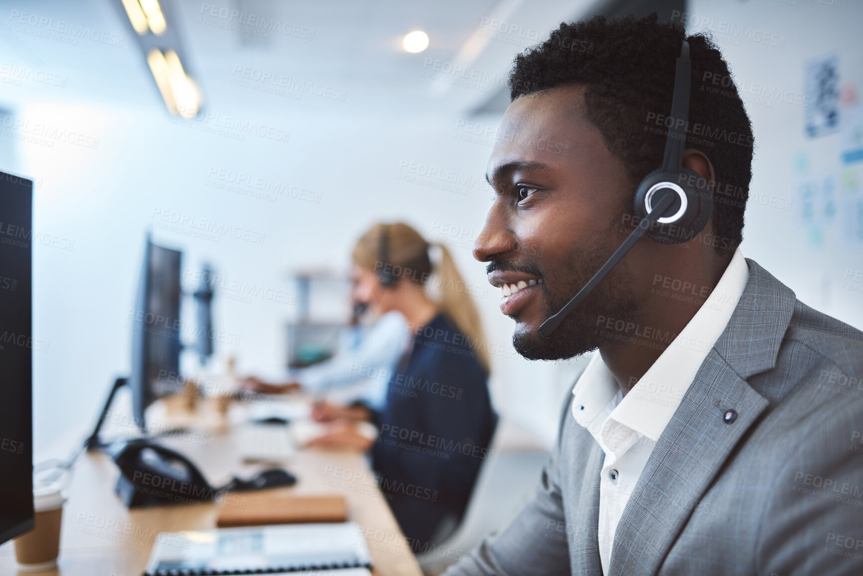 Buy stock photo Happy young african american call centre telemarketing agent talking on a headset while working on computer in an office. Confident friendly male consultant operating helpdesk for customer service and sales support