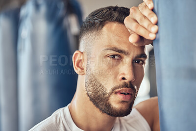 Buy stock photo Tired boxer taking a break from cardio routine. Portrait of exhausted mma fighter leaning on punching bag. Bodybuilder taking a break from combat routine. Strong trainer tired after boxing