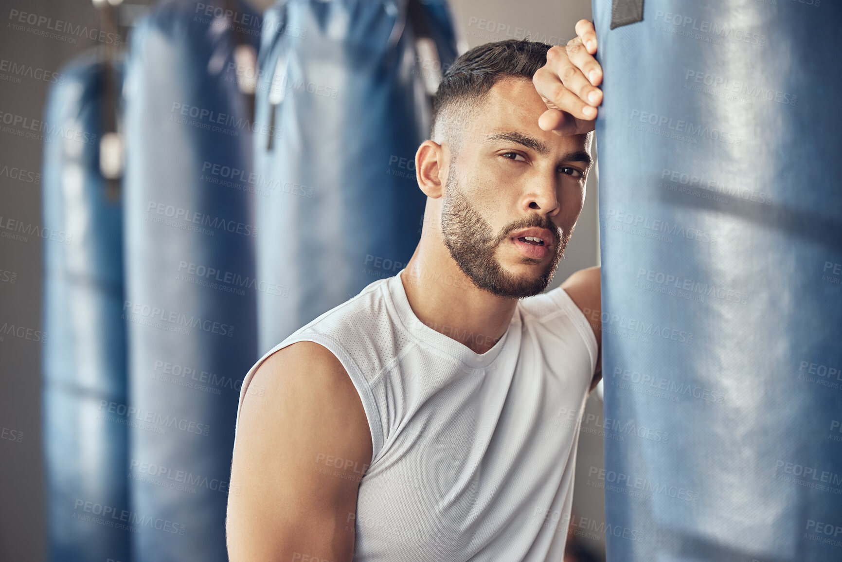 Buy stock photo Portrait of tired boxer leaning on punching bag. Exhausted mma fighter resting after workout in the gym. Bodybuilder boxing routine in the gym. Strong fit man tired after combat training