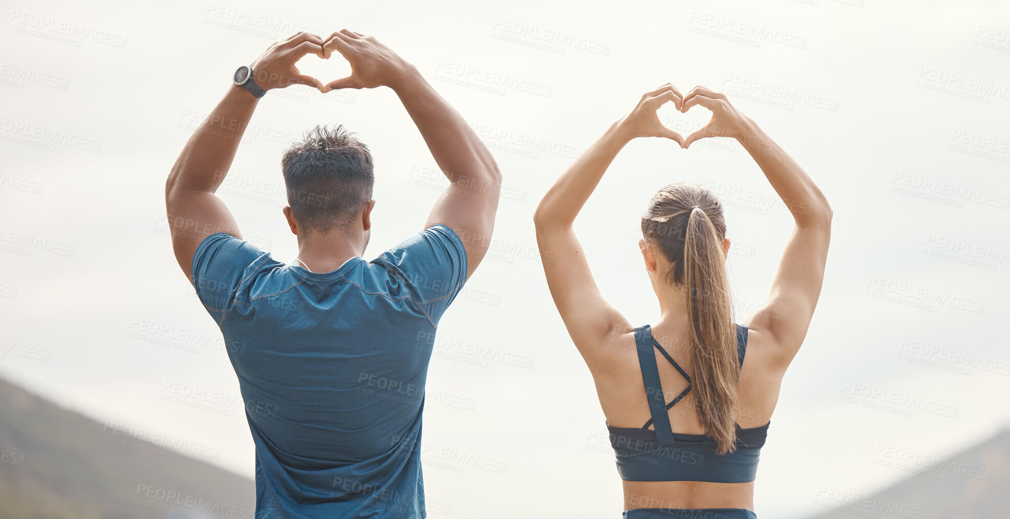 Buy stock photo Fit young man and woman from the back gesturing heart shapes with hands while exercising together outdoors. Two athletes caring for body with regular training workout or run. Endorsing and loving a healthy active lifestyle