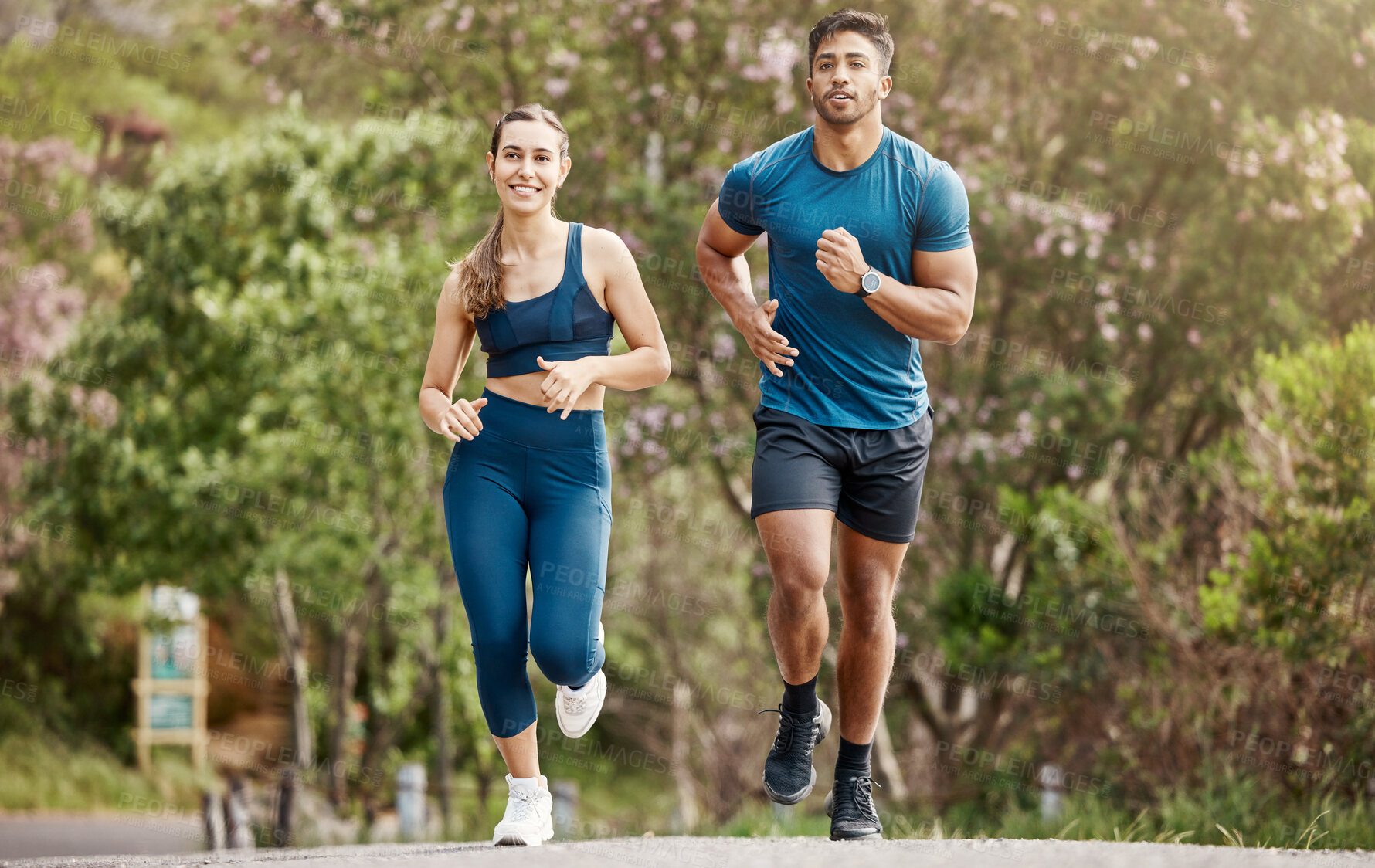 Buy stock photo Fit young man and woman running together outdoors. Interracial couple and motivated athletes doing cardio workout while exercising for better health and fitness at the park