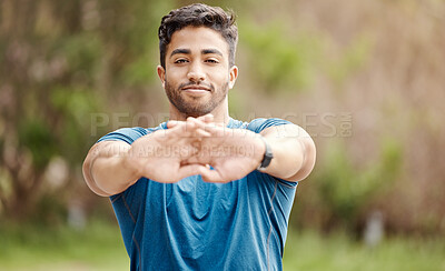 Buy stock photo Portrait of one fit young indian man stretching arms for warmup to prevent injury while exercising outdoors. Male athlete preparing body and muscles for training workout or run at the park