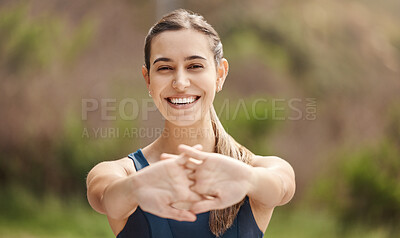 Portrait of one fit young mixed race woman stretching arms for warmup to prevent injury while exercising outdoors. Female athlete preparing body and muscles for training workout or run at the park
