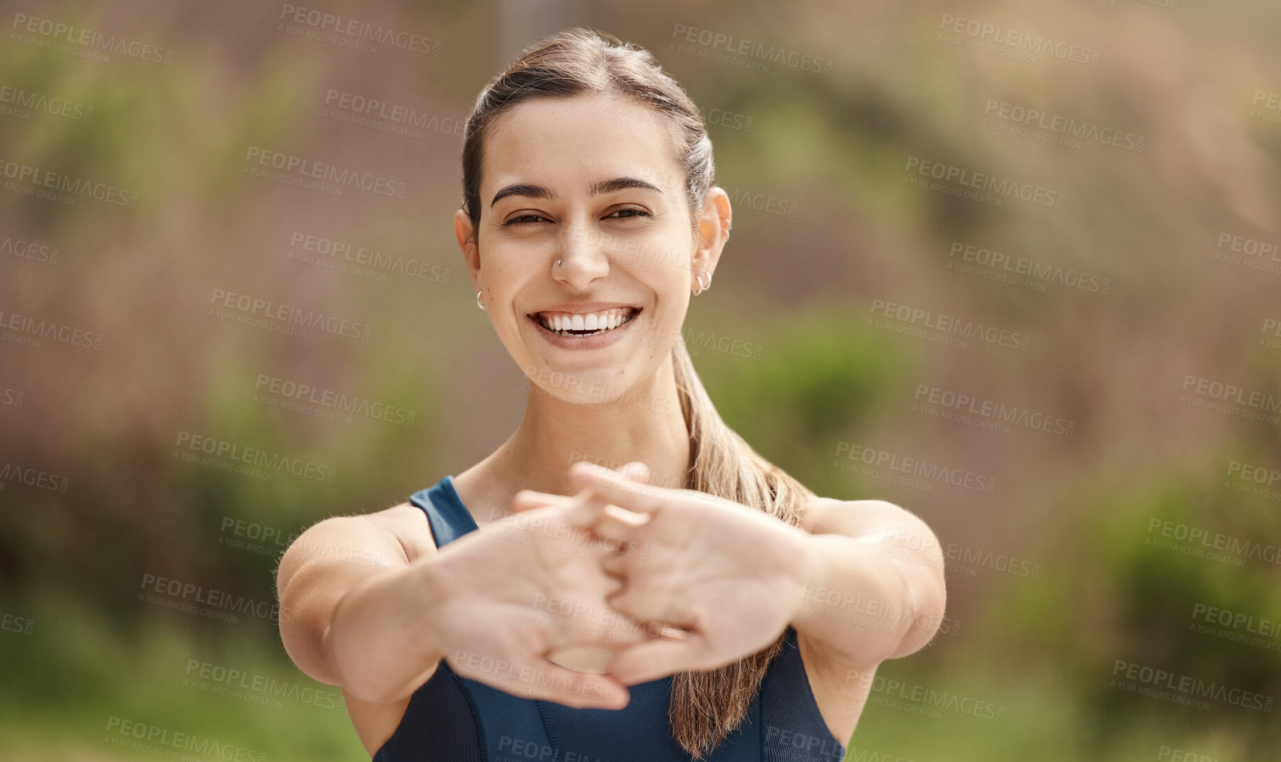 Buy stock photo Portrait of one fit young mixed race woman stretching arms for warmup to prevent injury while exercising outdoors. Female athlete preparing body and muscles for training workout or run at the park