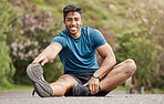 Portrait of one fit young indian man touching his feet and stretching legs for warmup to prevent injury while exercising outdoors. Muscular male athlete preparing body and muscles for training workout or run at the park