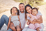 A happy mixed race family of four enjoying fresh air at the beach. Hispanic couple bonding with their daughters while having a picnic in a garden or park