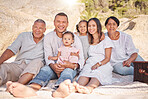 Portrait of a smiling mixed race family with little girls sitting  together at the beach. Adorable little kids bonding with their parents and grandparents while having a picnic at a park or garden