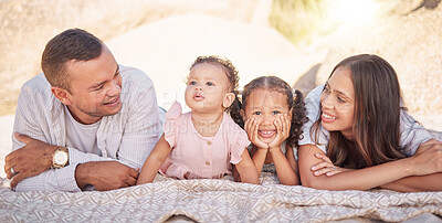 Buy stock photo A happy mixed race family of four enjoying fresh air at the beach. Hispanic couple bonding with their daughters while having a picnic in a garden or park